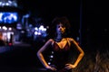 Stylish african american woman in night city. Woman standing with hands on waist