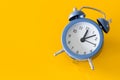 Stylish alarm clock showing five to twelve on a yellow background. Space for an inscription on the left Royalty Free Stock Photo