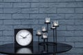 Stylish analog clock and candles on table