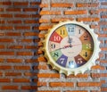 Stylish analog clock hanging on brick wall