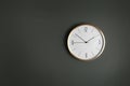 Stylish analog clock hanging on gray wall, space for text.