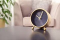 Stylish analog clock on table in living room, space for text.