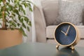 Stylish analog clock on table in living room