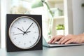 Stylish analog clock on table in office