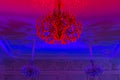 Stylish antique chandelier lit in pink and blue light.