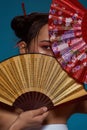 Stylish asian girl cover face with handheld fans