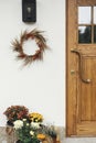 Stylish autumn wreath hanging at modern lantern, pumpkins and flowers at wooden door outdoor. Fall decor and arrangement of Royalty Free Stock Photo