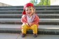 Stylish baby sitting on stairs in summer