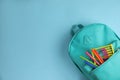 Stylish backpack with different school stationary on light blue background, top view Royalty Free Stock Photo