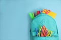 Stylish backpack with different school stationary on light blue background. Space for text Royalty Free Stock Photo