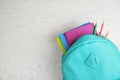 Stylish backpack with different school stationary on white wooden table, top view