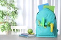 Stylish backpack with different school stationery on table. Space for text