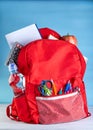 Stylish backpack with various school stationary on a white wooden table on a blue background Royalty Free Stock Photo