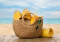 Stylish bag with beach accessories on wooden surface near seashore Royalty Free Stock Photo