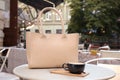 Stylish bag and cup of coffee on white table in outdoor cafe Royalty Free Stock Photo