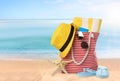 Stylish bag with different accessories on sandy beach, space for text Royalty Free Stock Photo