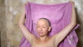 Stylish bald woman wipes her head with a towel after a shower. adventures of strange people , humor.