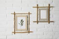 Stylish bamboo frames hanging on brick wall