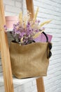 Stylish beach bag with beautiful bouquet of wildflowers, sunglasses and magazines on shelf indoors