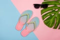 Stylish beach flip-flops on pink and blue pastel background with monstera leaf and sunglasses, top view. Summer concept Royalty Free Stock Photo