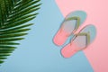 Stylish beach flip-flops on pink and blue pastel background with palm leaf, top view. Summer concept with copy space. Royalty Free Stock Photo