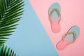 Stylish beach flip-flops on pink and blue pastel background with palm leaf, top view. Summer concept with copy space. Royalty Free Stock Photo