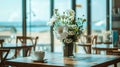 Stylish beachside cafe with large windows, fresh coffee on table, and white flowers in vase Royalty Free Stock Photo