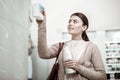 Stylish beaming woman choosing her favorite items on pharmacy store