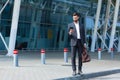 Stylish bearded business man with travel bag and mobile phone in hands walks on city street modern urban background. Businessman Royalty Free Stock Photo