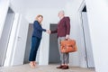 Stylish bearded businessman holding brown leather bag shaking hand of partner