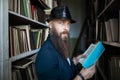 Stylish bearded man with book in library