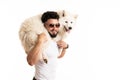 Stylish bearded man in glasses holds samoyed dog on his back, smiling and looking at the camera Royalty Free Stock Photo