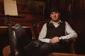 stylish man in hat is sitting in an armchair in a chic retro interior of restaurant Royalty Free Stock Photo