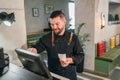 Stylish bearded smiling waiter dressed black uniform processing customer orders using point of sale order terminal system touch