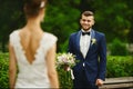 Stylish and bearded young brutal man in a smart suit holding the bouquet and looking on his sexy and beautiful model