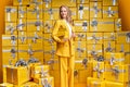 Stylish beautiful blonde woman wearing yellow suit holding nice handbag