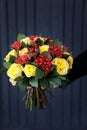 Stylish beautiful bouquet in yellow and coral colors of roses, Jatropha multifida and other plants in the florist hand