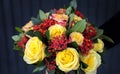 Stylish beautiful bouquet in yellow and coral colors of roses, Jatropha multifida and other plants in the florist hand