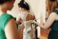 Stylish beautiful bridesmaids helping gorgeous brunette bride in white dress get ready for wedding, morning preparations, woman Royalty Free Stock Photo