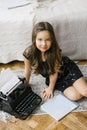 Stylish beautiful chubby girl in a black dress sitting near the old typewriter Royalty Free Stock Photo