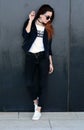 Stylish beautiful ginger young woman standing by the wall on the street. Streetstyle photo shoot. Royalty Free Stock Photo