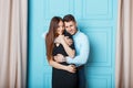 Stylish beautiful young couple hugging near a blue vintage wall.