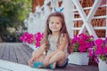 Stylish beautifull cute baby girl with brunette hair posing on wooden garden full of flowers wearing tiny jeans shirts and airy sk