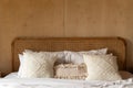 Stylish Bedroom corner with rattan headboard and bed with soft white pillows setting with plywood wall on the background / cozy in Royalty Free Stock Photo
