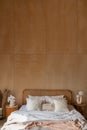 Stylish Bedroom corner with rattan headboard and bed with soft white pillows setting with  plywood wall on the background / cozy Royalty Free Stock Photo