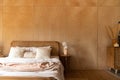 Stylish Bedroom corner with rattan headboard and bed with soft white pillows setting with  plywood wall on the background / cozy Royalty Free Stock Photo