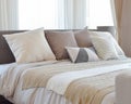 Stylish bedroom interior design with brown patterned pillows on bed and decorative table lamp.