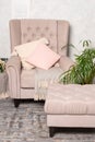 Stylish beige armchair with pink pillows in a bright minimalist interior.