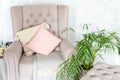 Stylish beige armchair with pink pillows in a bright minimalist interior.