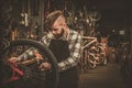 Stylish bicycle mechanic doing his professional work in workshop